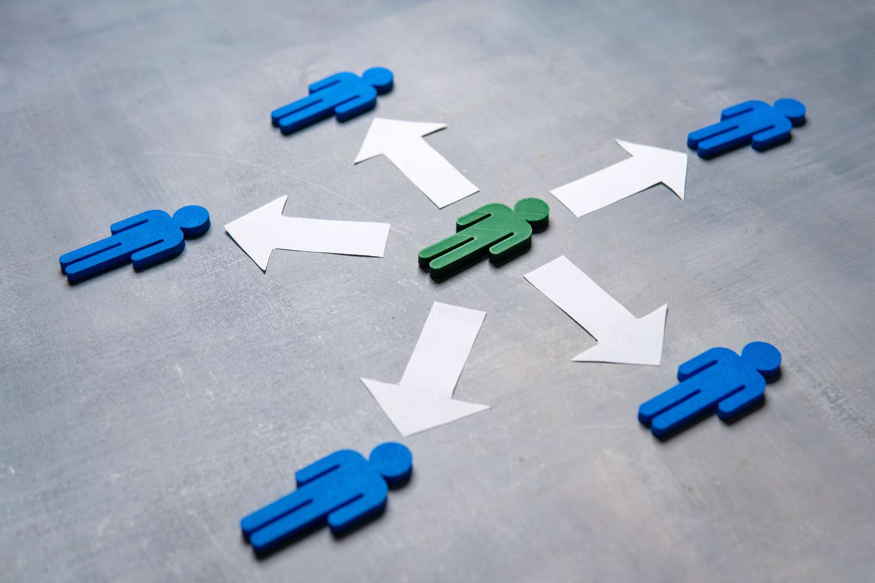 Ein Schaubild zeigt ein grünes Männchen in der Mitte, von welchem weiße Pfeile zu 5 blauen Männchen drumherum ausgehen, als Sinnbild für Arbeitswelten ohne Chefstruktur.