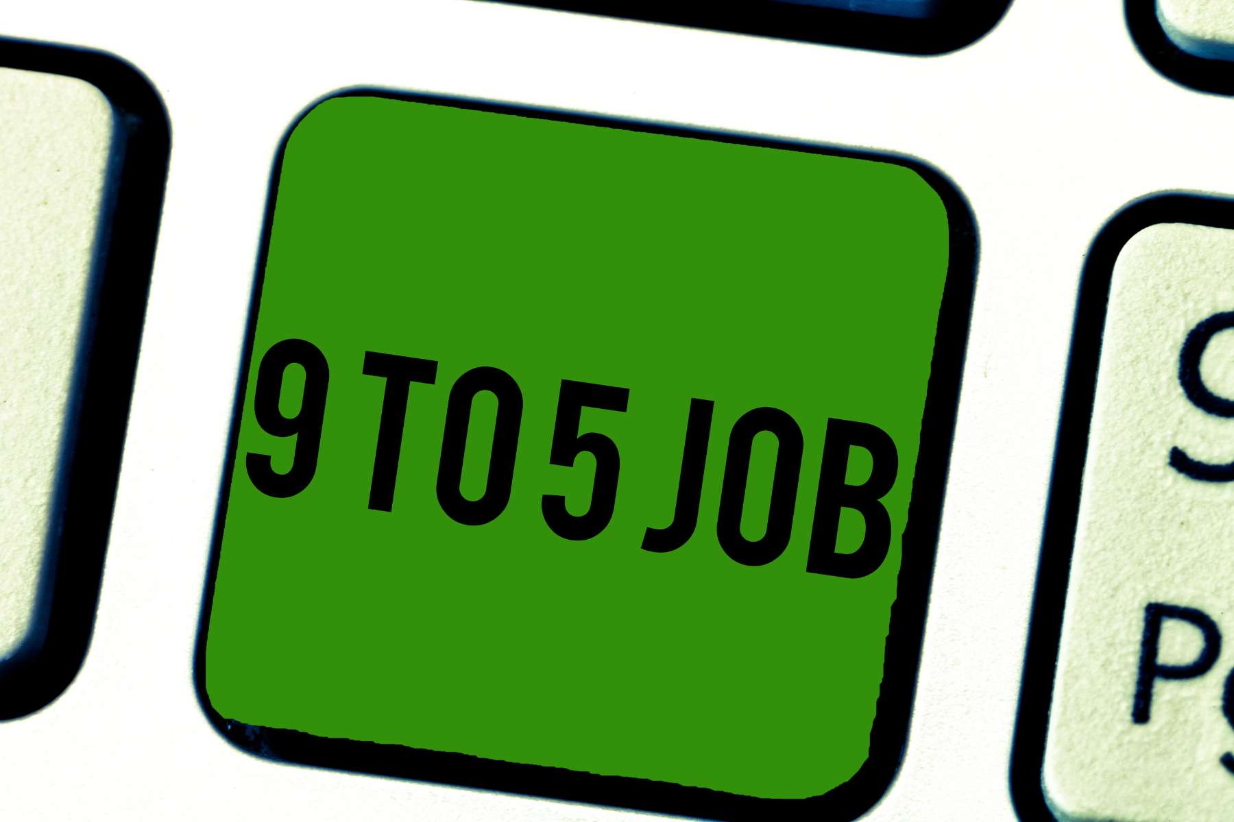 Nahaufnahme einer weißen Tastatur, auf der eine grüne Taste mit dem Schriftzug 9 TO 5 JOB zu sehen ist.