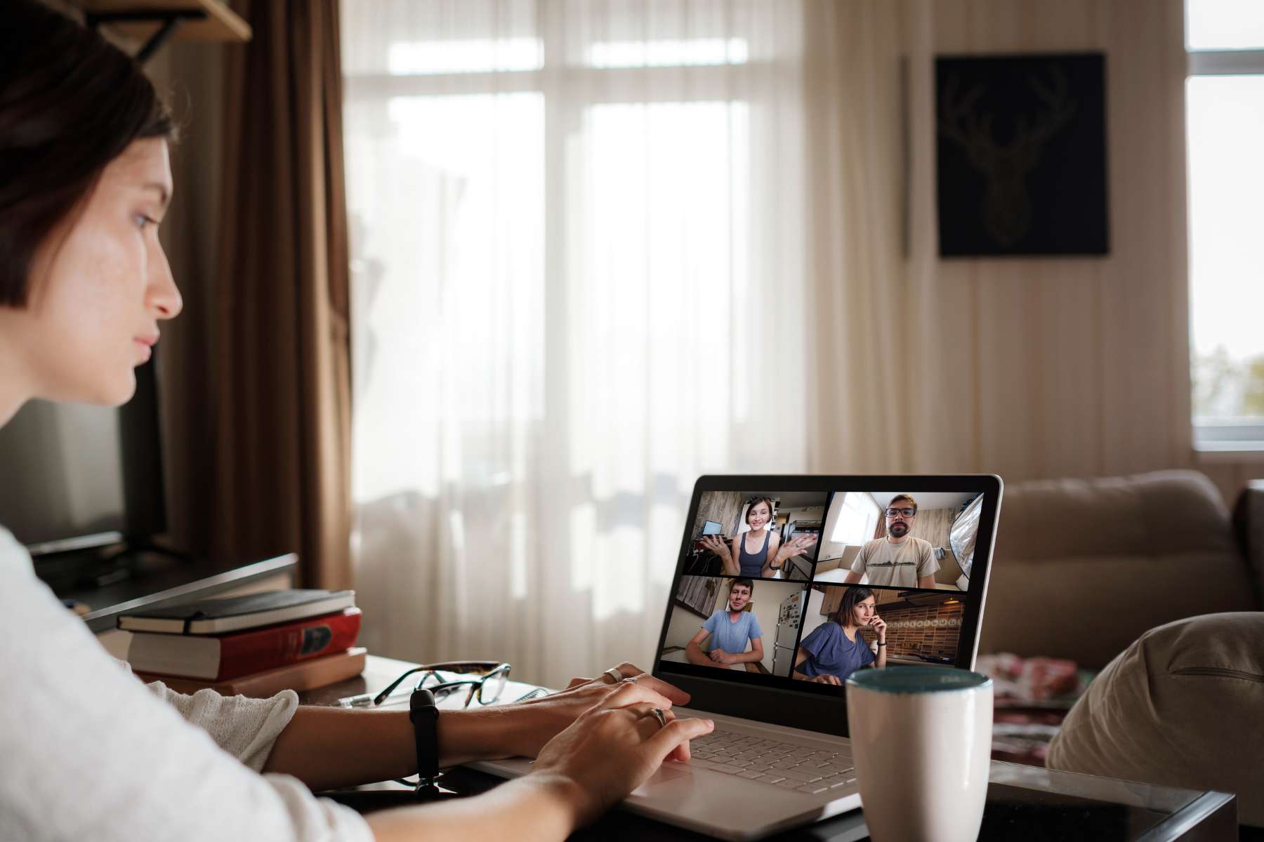 Eine junge Frau arbeitet im Homeoffice, sitzt vor ihrem Laptop und nimmt gerade an einem Meeting teil, als Sinnbild für Einsamkeit im Job.