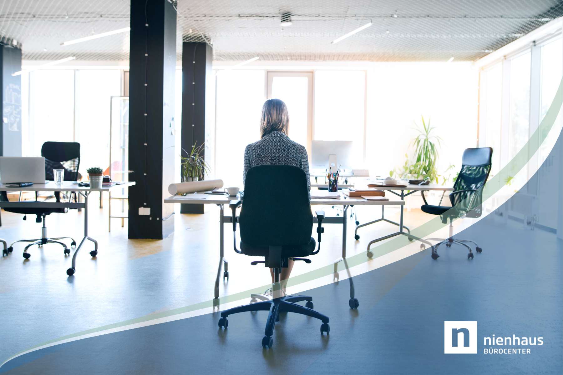 Eine weibliche Angestellte sitzt alleine an einem Schreibtisch in einem sonst leeren und weitläufigen Büro, als Sinnbild für die Thematik Einsamkeit im Job.
