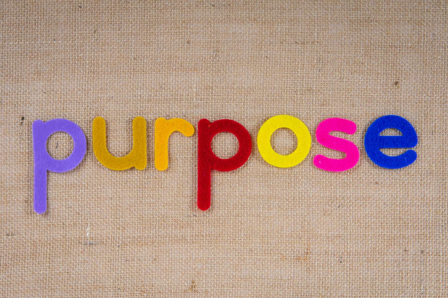 Das Wort purpose liegt in bunten Buchstaben auf einer Unterlage aus Leinen.