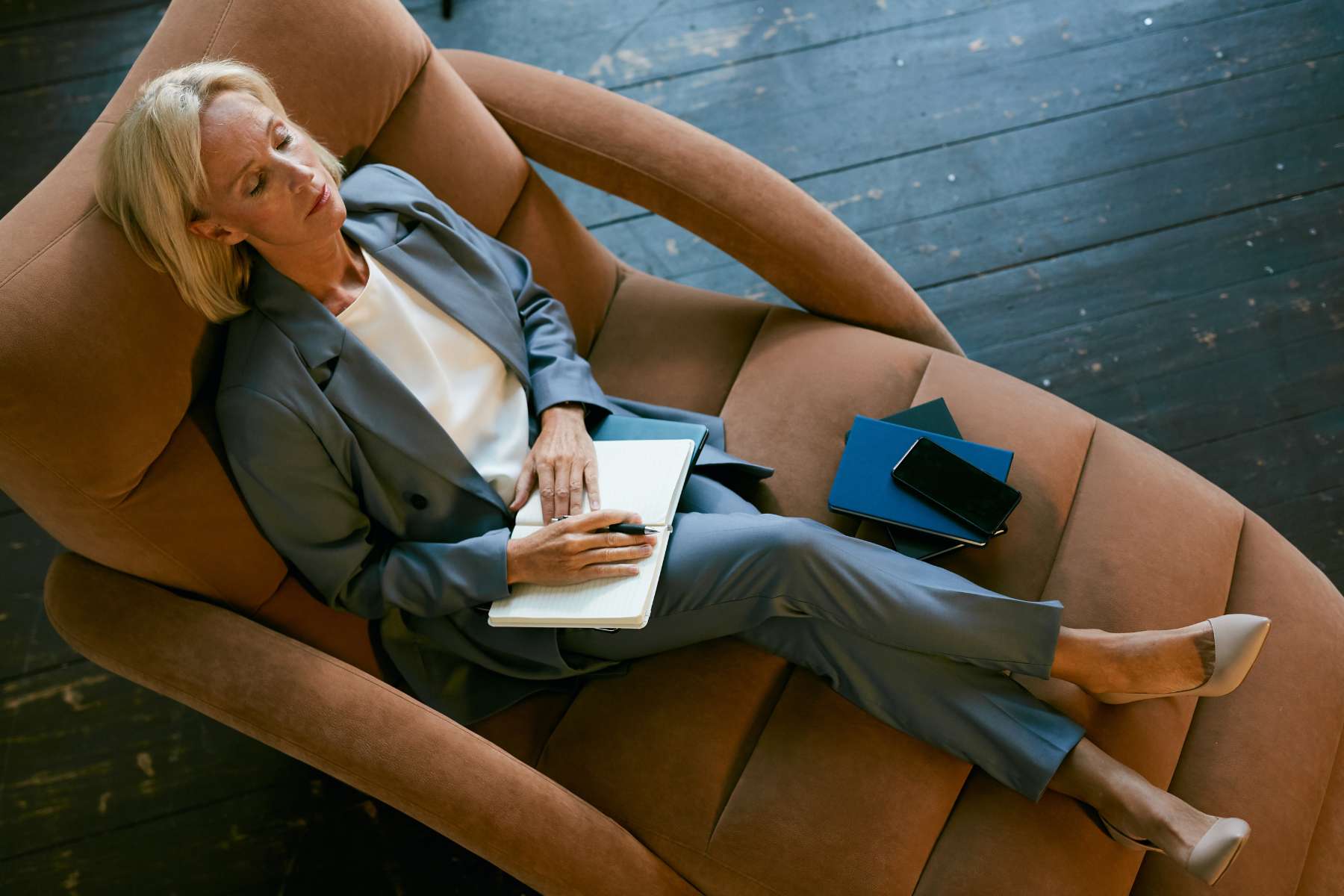 Eine Geschäftsgrau mittleren Alters liegt in einem Loungesessel und macht eine kurze Pause von der Arbeit.