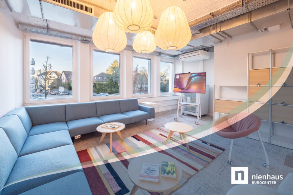 Modern eingerichteter New Work Empfangsbereich bzw. Chill-Out-Area mit gemütlichem blauen Sofa, buntem Teppich und stylischen Deckenleuchten.