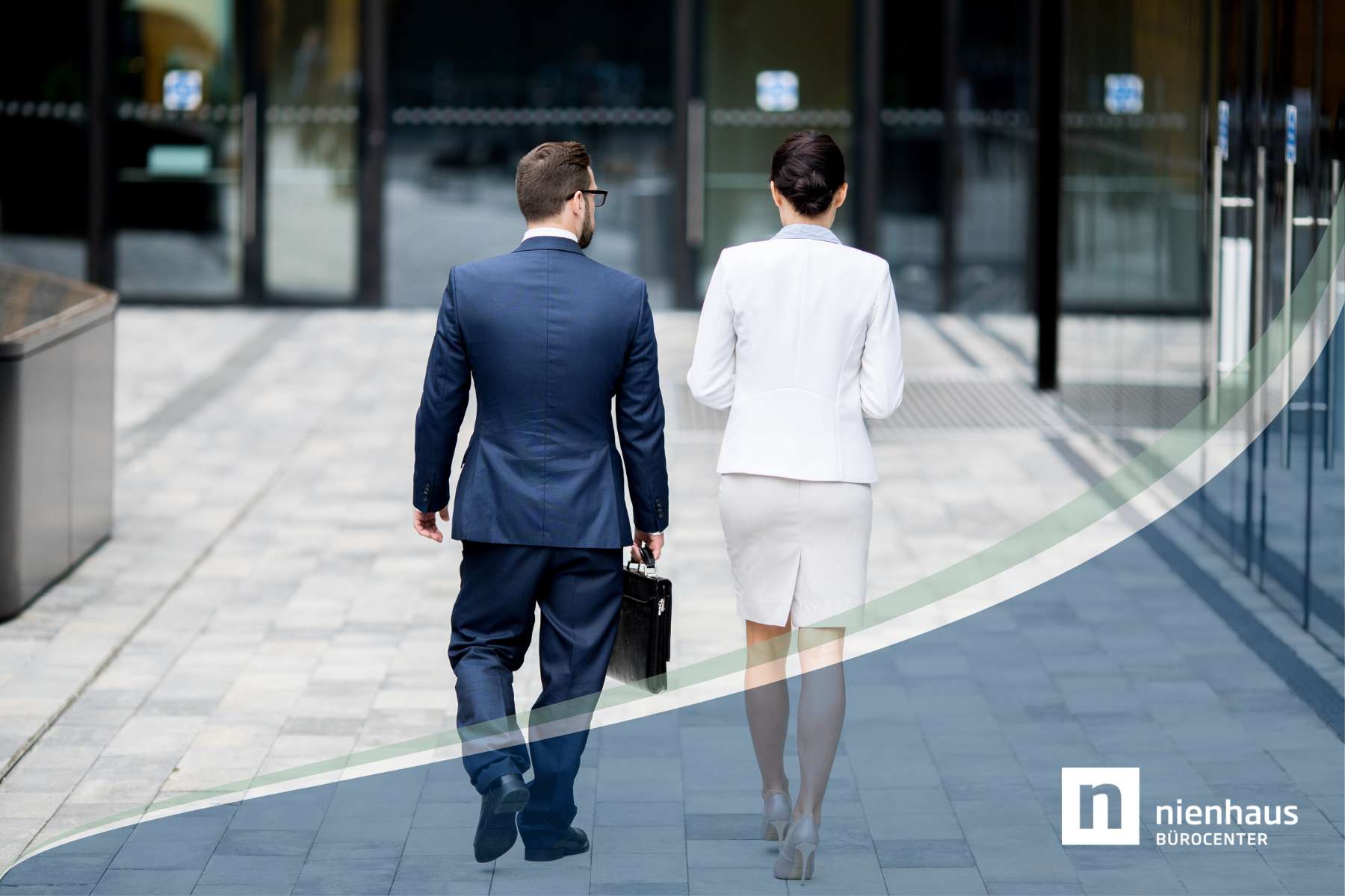 Eine Geschäftsfrau und ein Geschäftsmann sind von hinten zu sehen, während sie auf ein Büro zugehen, als Sinnbild für das Thema Return to Office.