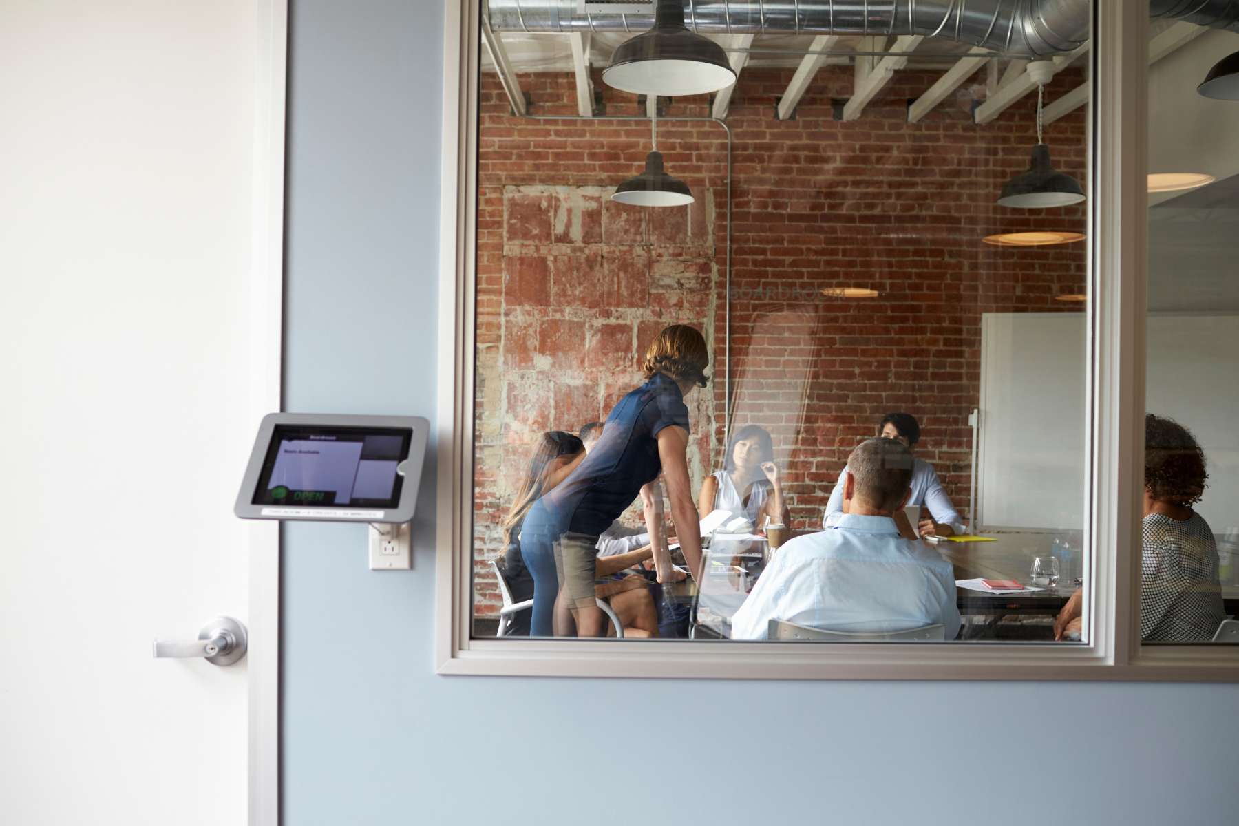 Meeting im Smart Office, durch Glaswand sichtbares Team im modernen Konferenzraum.