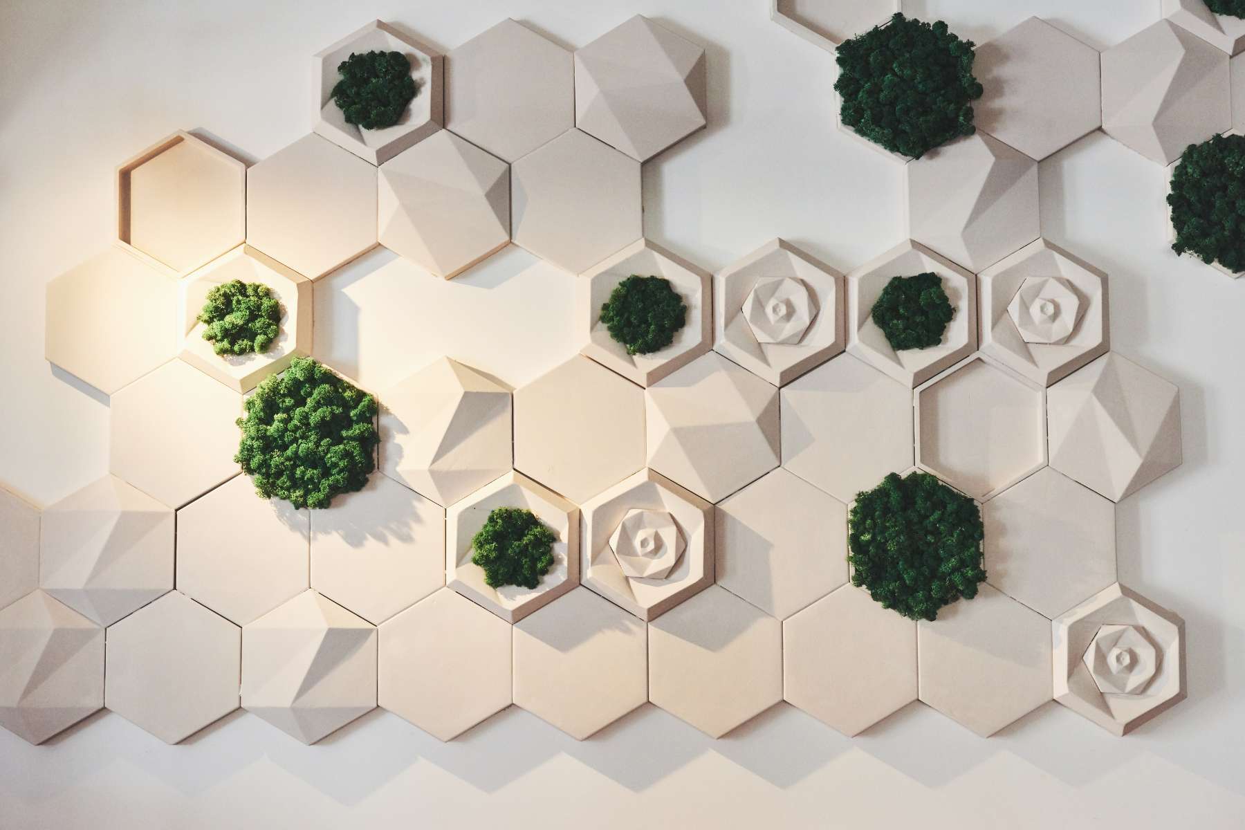 Beiges Wandmosaik mit floralem Muster und biophilen Elementen in Form von Moos.